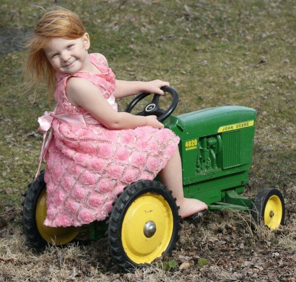 Une fille conduisant un tracteur électrique enfant John Deere